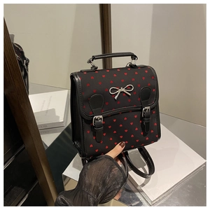 Detail of black canvas backpack with red heart prints and silver bow metal buckle accent