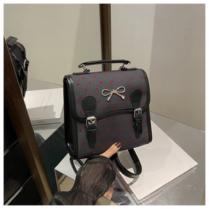 Detail of dark grey canvas backpack with red heart patterns and silver bow buckle