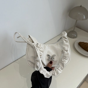 Minimalist white pleated underarm bag with silver butterfly buckle in a lifestyle setting