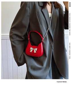 Macro detail of red mini crossbody bag with silver bow buckle and elegant chain strap
