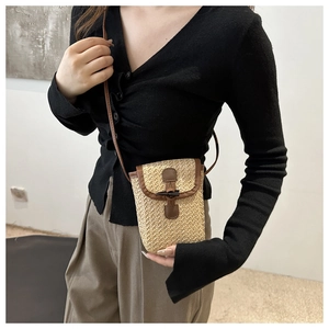 Detail of summer straw crossbody bag with brown faux leather trim and olive button closure