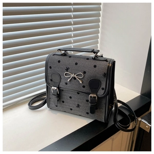 Detail of grey polka dot canvas bag with silver bow accent and black faux leather handle