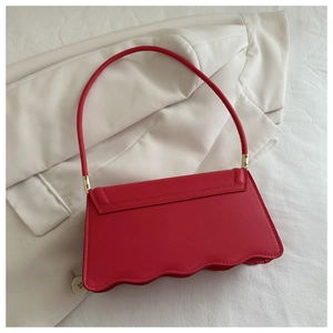 Détail du sac à bandoulière magenta avec bord festonné sur fond de costume blanc