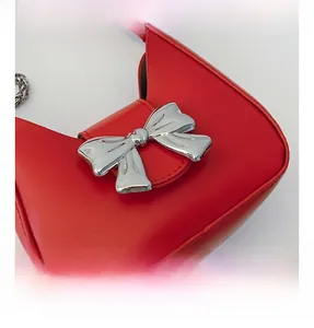 Detailed close-up of large silver metallic bow hardware on a red leather mini bag