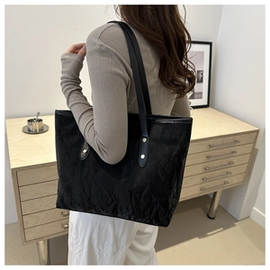 Lifestyle shot of a black pleated tote bag with silver studs and long shoulder straps