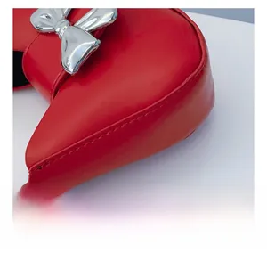 Detailed macro view of red leather bag with silver metal bow and precise stitching