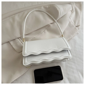 Vue détaillée du sac blanc à bords ondulés sur une veste beige avec un smartphone témoin