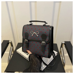 Close-up of heart print canvas bag with black leather handles and silver bow detail