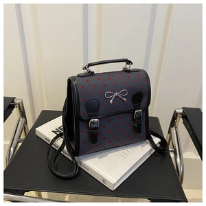 Detail view of mini heart-print canvas bag with leather straps and silver bow buckle