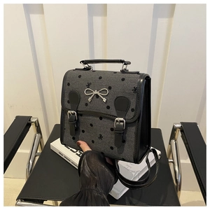 Detail of grey polka dot mini backpack with silver bow buckle and faux leather straps