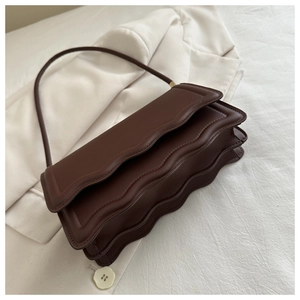 Détail du sac à bandoulière marron foncé à bords festonnés et structure en accordéon
