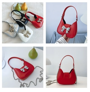 Detail of trendy mini half-moon bag with large silver metal bow and metal chain strap