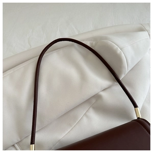 Gros plan d'un sac porté épaule en cuir rouge foncé avec détails en métal doré
