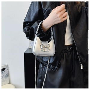 Detailed view of silver mini bow handbag with metallic finish and thin chain strap