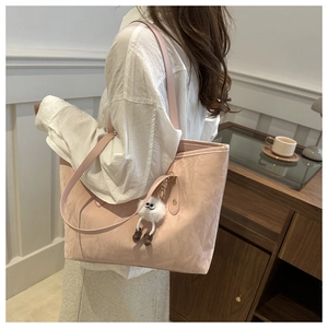 Detailed close-up of a pink tote bag featuring crinkled texture and a cute plush charm