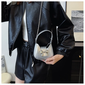 Close-up of a silver metallic mini crescent bag with a bow detail and chain strap