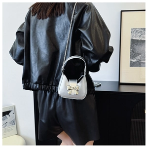 Rear view of a model wearing the silver mini chain bag with large metallic bow detail