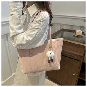 Detailed texture of pink tote bag with cute plush monster charm and long shoulder strap