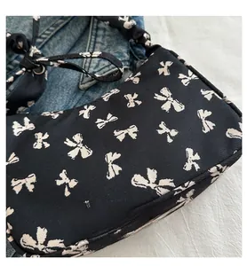 Detail of floral canvas underarm bag with bow print and pleated shoulder strap design