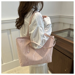 Detail of light pink tote bag with crinkled texture fabric on female model shoulder