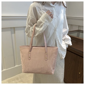 Pink tote bag with pleated texture and gold hardware on model in a minimalist setting