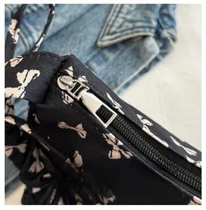 Close-up of the smooth silver metal zipper and bow print on black nylon shoulder bag