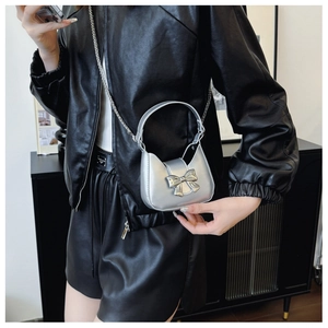 Silver mini bow handbag worn cross-body against a black leather outfit for a chic look