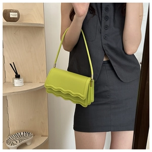 Hellgrüne Schultertasche mit Wellenkante und Goldverzierung getragen von Model