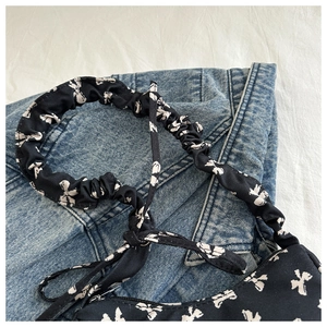 Close-up of black canvas bag with white floral patterns and scrunchie strap detail