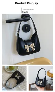 Detail of a mini black crossbody bag with a large golden metal bow buckle and chain