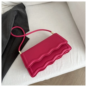 Dettaglio di una borsa a spalla color rosa acceso con design a patta ondulata a strati