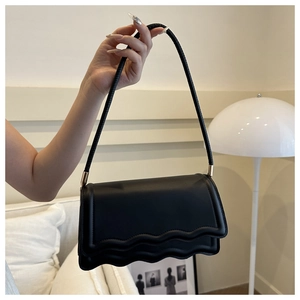 Détails du sac à main en cuir noir avec bordure ondulée et ferrures métalliques dorées