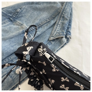 Close-up of black nylon bag with white bow print and stylish gathered drawstring strap