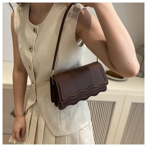 Dettaglio borsa sottobraccio in pelle PU marrone scuro con patta a onde e fibbie in metallo oro