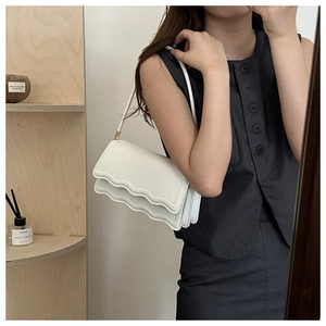 Detail einer weißen minimalistischen Wellen-Schultertasche mit mehrlagiger Harmonika-Struktur