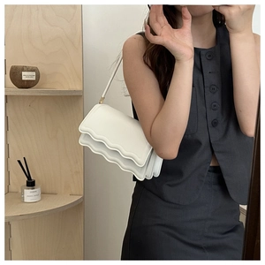 Detail view of white shoulder bag featuring unique scalloped edges and minimalist design