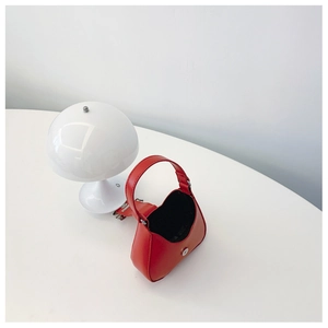 Close-up of a red mini bow handbag with silver magnetic closure and hobo design style