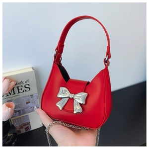 Detail of trendy red mini handbag featuring a silver metal bow and elegant chain strap
