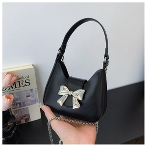 Detail of black mini handbag featuring silver bow buckle and elegant metal chain strap
