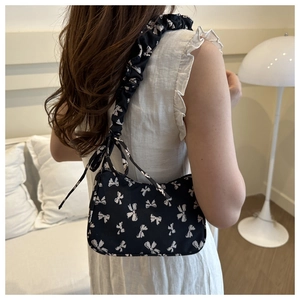 Detail of black underarm bag with white bow print and gathered ruched shoulder strap