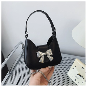 Close-up of black half-moon handbag with a large silver metal bow and chain strap