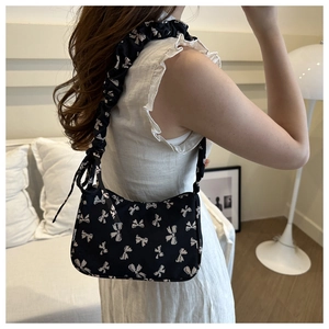Detail of canvas shoulder bag with bow prints and shirred strap on model side view