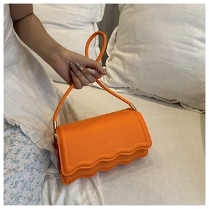 Détail d'un sac à main orange vif avec bords ondulés et finition en cuir PU mat lisse