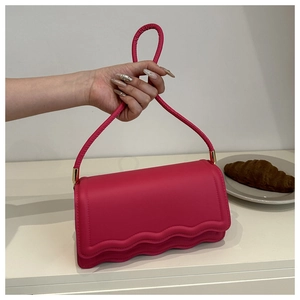 Détail du sac à main rose fuchsia avec bordure ondulée et finitions métalliques dorées