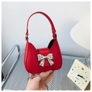 Detailed macro view of red leather mini bag with silver bow hardware and metal chain strap