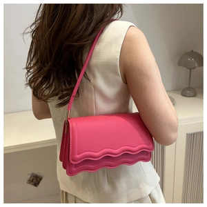 Dettaglio della borsa a tracolla rosso rosa con doppia patta a onda e pelle trapuntata