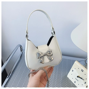 Detailed view of mini white bow handbag with silver clasp and elegant chain strap