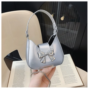Close-up of silver crescent mini bag with metal bow detail on vintage book