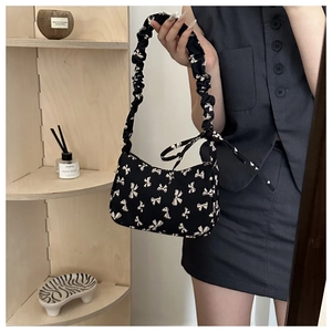 Detail of floral nylon crescent bag featuring ruffled handle and bow ribbons