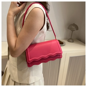 Elegante borsa a tracolla rosa con patta a onde mostrata in un ambiente di vita reale